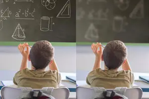 A young boy sitting in a classroom is looking at a blackboard with mathematical equations and shapes written on it.