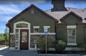 The front of a house with stone wall, brown door, and sign indicating reserved parking