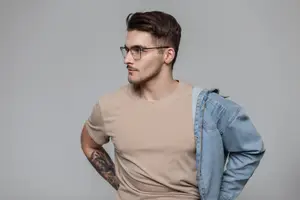Man in glasses and denim jacket with his hand in his pocket