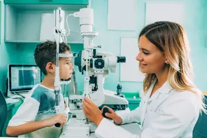 A young boy is having his eyes examined by a female doctor in a medical clinic.