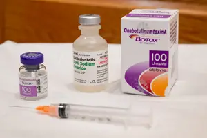 A white table displays a Botox vial, a syringe, and a box with a label.