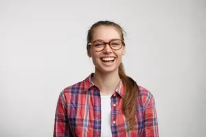 Young woman with glasses and a plaid shirt smiling for the camera