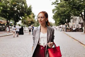 woman wearing a blazer and glasses standing in the street