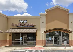 Eye-Deal Vision optometrist and optical storefront with a cloudy sky in the background