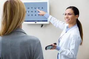 beautiful optician doing eye test with eye chart on her patient in ophthalmology clinic.