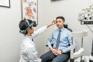 An eye doctor examining a patient's eye with a medical device in a clinic.