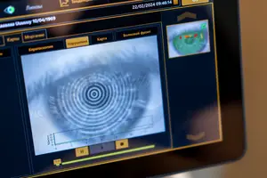 A medical imaging screen displays a spiral-like pattern with a green circle and red dots, likely related to eye health analysis, with a time stamp of 22/02/2024 09:46:14 and various navigation buttons visible.