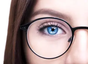 Close-up of a woman's face with blue eyes and black glasses