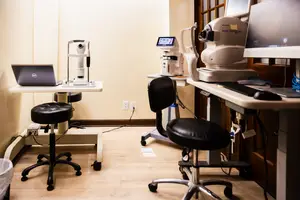 An eye examination room with medical equipment and a laptop on a table