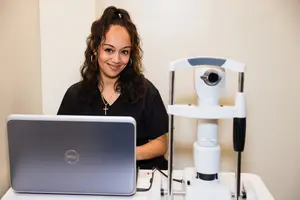 A staff sitting in front of her laptop and eye exam machine at the Eyesite Vision Center in Hoboken, NJ.