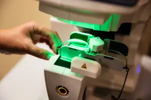 A person's hand is adjusting a device that has a green light on it.