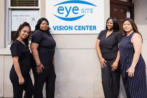Four women in black clothing standing in front of an EyeSite Vision Center sign