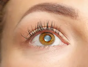 Close-up of a woman's eye with a blue contact lens and long eyelashes.