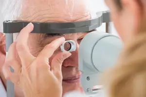 An older man is having his eyes examined by a Rancho Mirage, California eye doctor using an ophthalmoscope.