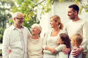A family of four with two older people smiling in a garden