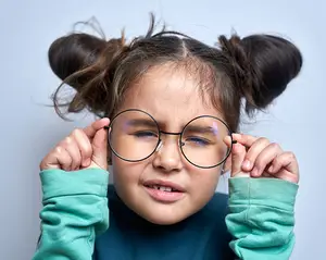 A girl wearing glasses and looking down while holding the frames