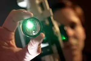 Close-up of a person holding a green lens, possibly examining it with a microscope