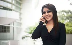 Woman wearing black clothing talking on a cellphone in front of a building