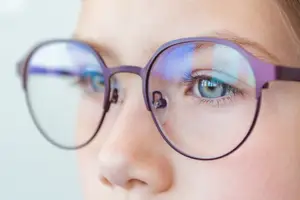 a girl with blue eyes wearing glasses looking straight ahead