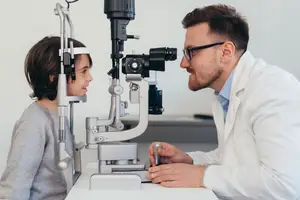 Doctor examining young girl's eyes in an examination room.