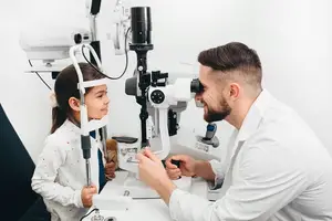 A doctor examines a child's eyes with an ophthalmoscope
