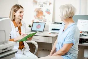 An older woman consults with an optometrist in an office setting.