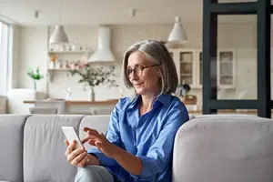 A woman sitting on a couch and holding a phone