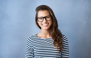 Woman with glasses smiling at the camera in a studio setting