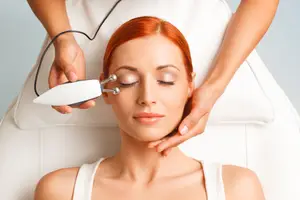 A woman is getting a beauty treatment with a facial massager in a spa.