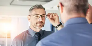 businessman adjusting glasses while another man watches