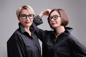 Two women standing and smiling with one hand on the other's head