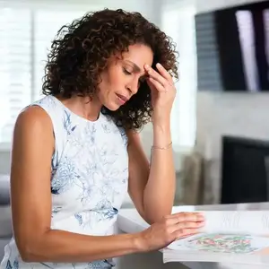A woman sitting and reading a book while holding her head with her hand