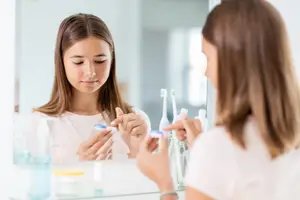 Two women brushing their teeth in front of a mirror