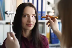 An optometrist examining a patient's eye with a penlight.