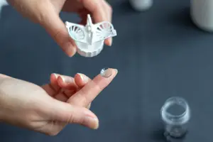 A hand with a fingertip lens is holding a lens case with a butterfly design