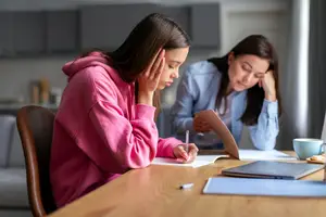 Two young women sitting at a table and working on a project