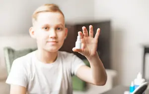 A boy showing a small bottle of medication in his hand