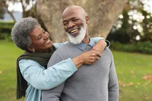 Senior black couple smiling and hugging in a park