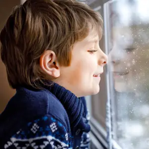 A boy looking out of a window during snowy weather