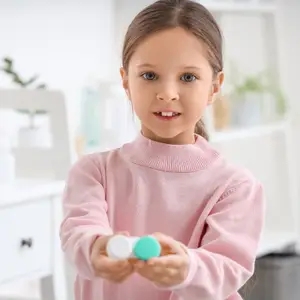 A young girl holding a bottle of eye drops