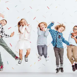 Five children jumping in the air in front of a white background with multicolored confetti