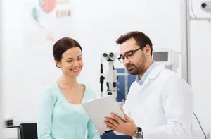 An eye doctor is showing a patient a tablet in an eye clinic.