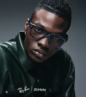 A man wearing Ray-Ban glasses and a green leather shirt poses for a photo