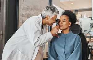 A doctor examining a woman's ear with an otoscope