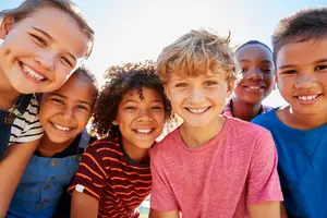 A group of children are smiling and posing for a picture in an outdoor area.