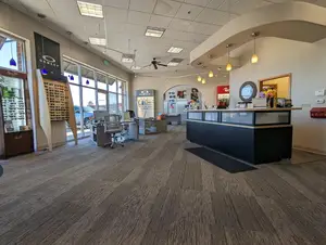 The interior of an office building has glass windows, a counter, chairs, and a ceiling fan.
