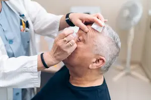 Doctor administering eye drops to an elderly patient