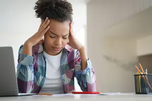 woman sitting in front of a laptop looking stressed