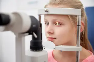 A young girl having her eyes examined by an optometrist using a slit lamp