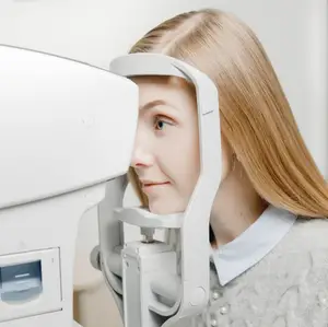 A girl with blonde hair is having her eyes checked by an optometrist using an eye exam machine